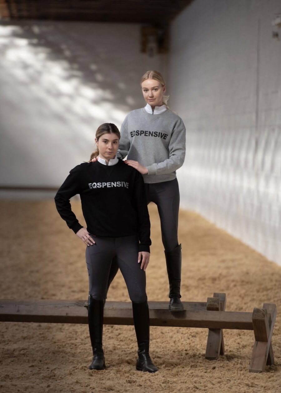 Two women in casual hoodies and leggings posing indoors.