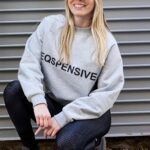 Person wearing a gray sweatshirt with the word 'EXPENSIVE' printed on it.