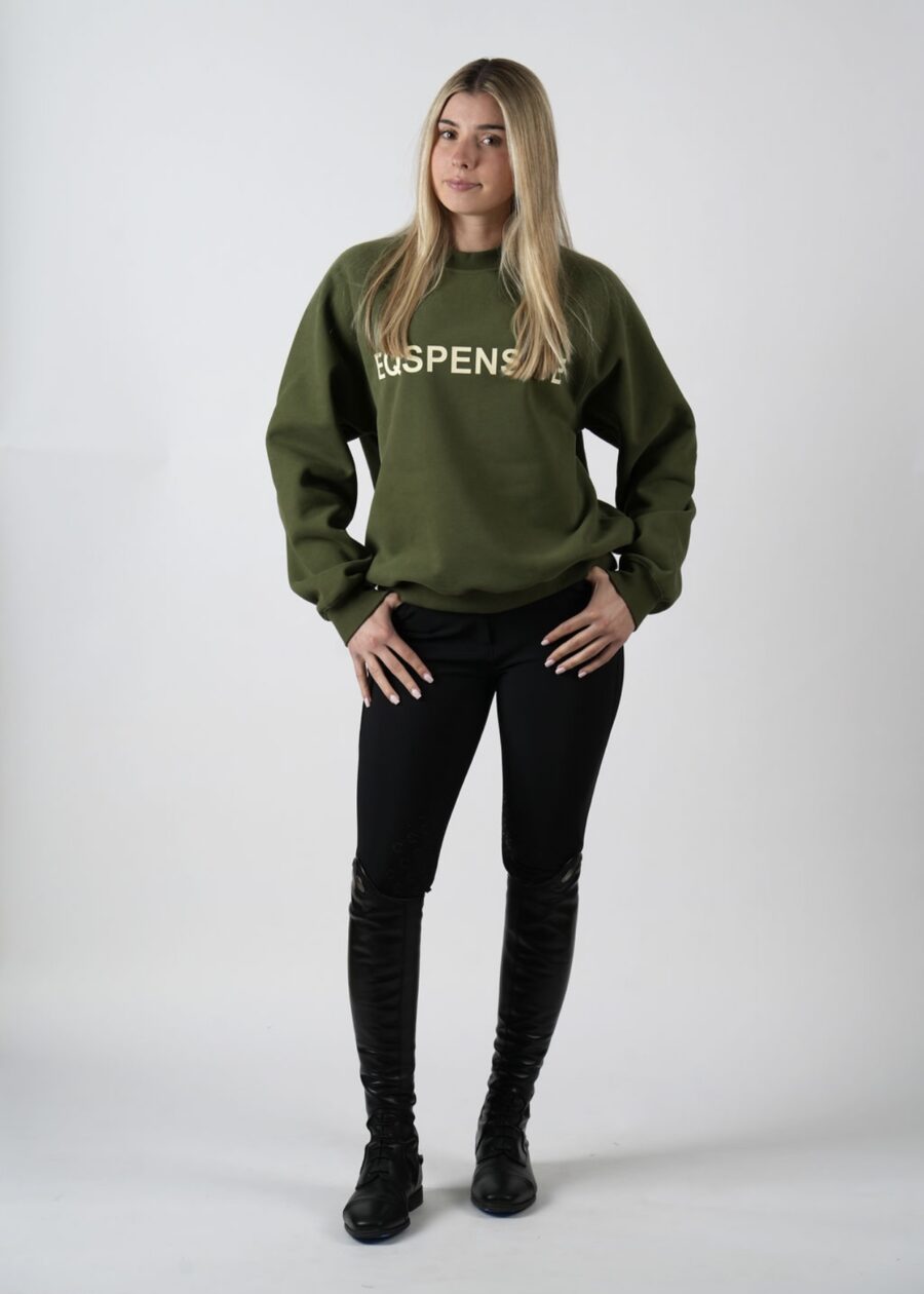 Woman in green Aspen sweatshirt and black jeans posing.