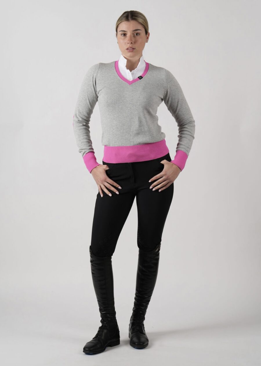Person wearing a gray sweater with pink cuffs and collar, black pants, and black boots.