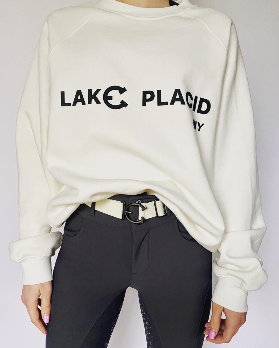 Casual outfit featuring a white Lake Placid sweatshirt and black pants with a patterned belt.