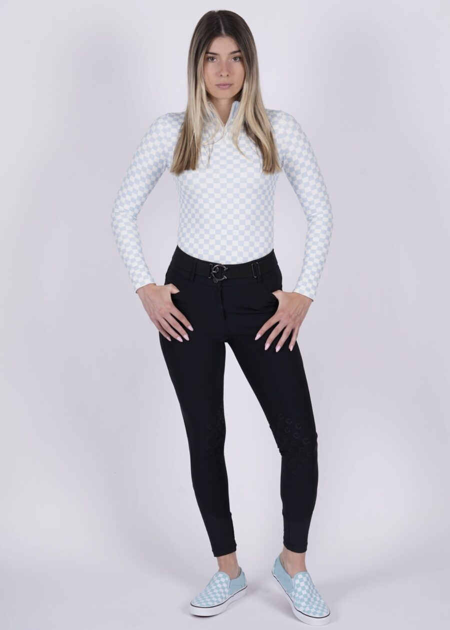 Woman in white long-sleeve shirt and black pants posing against a white background.