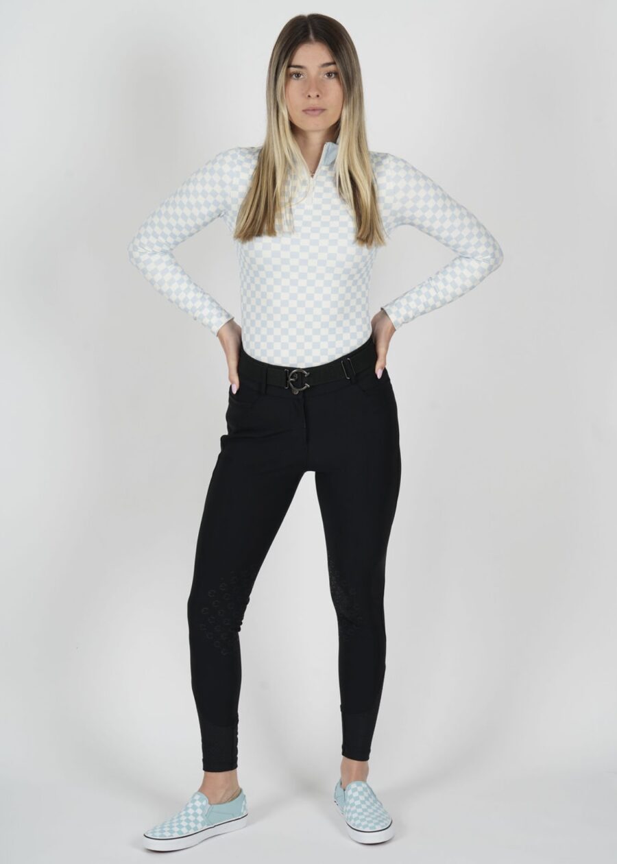 Woman in white long-sleeve top and black pants posing confidently.