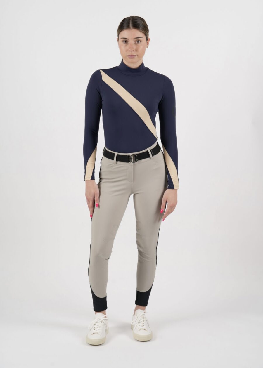 Woman wearing a stylish navy and beige long-sleeve top with beige pants and a belt.