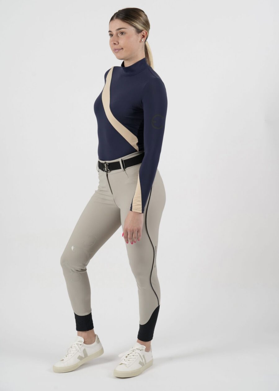 Woman modeling beige and navy riding pants with a belt and boots.
