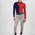 Woman wearing a color-blocked red and navy long-sleeve top with beige pants and black boots.