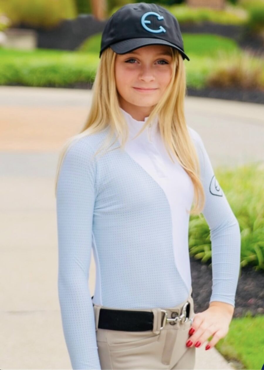 Young woman in a light blue jacket and beige cap outdoors.