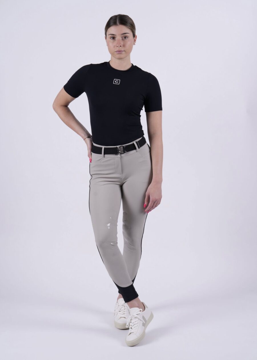 Man wearing a fitted black t-shirt and beige pants with suspenders.