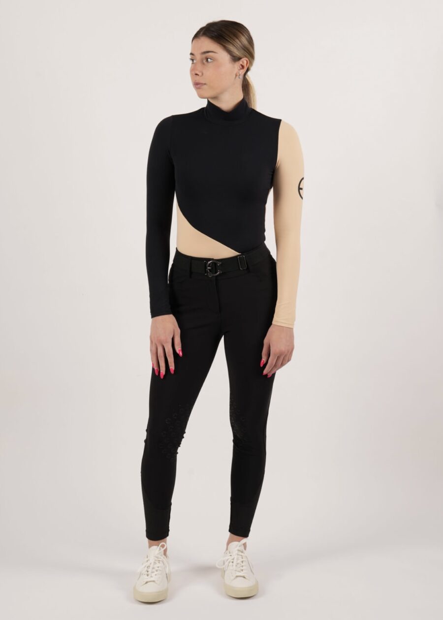 Woman in asymmetrical black top and black skinny pants.