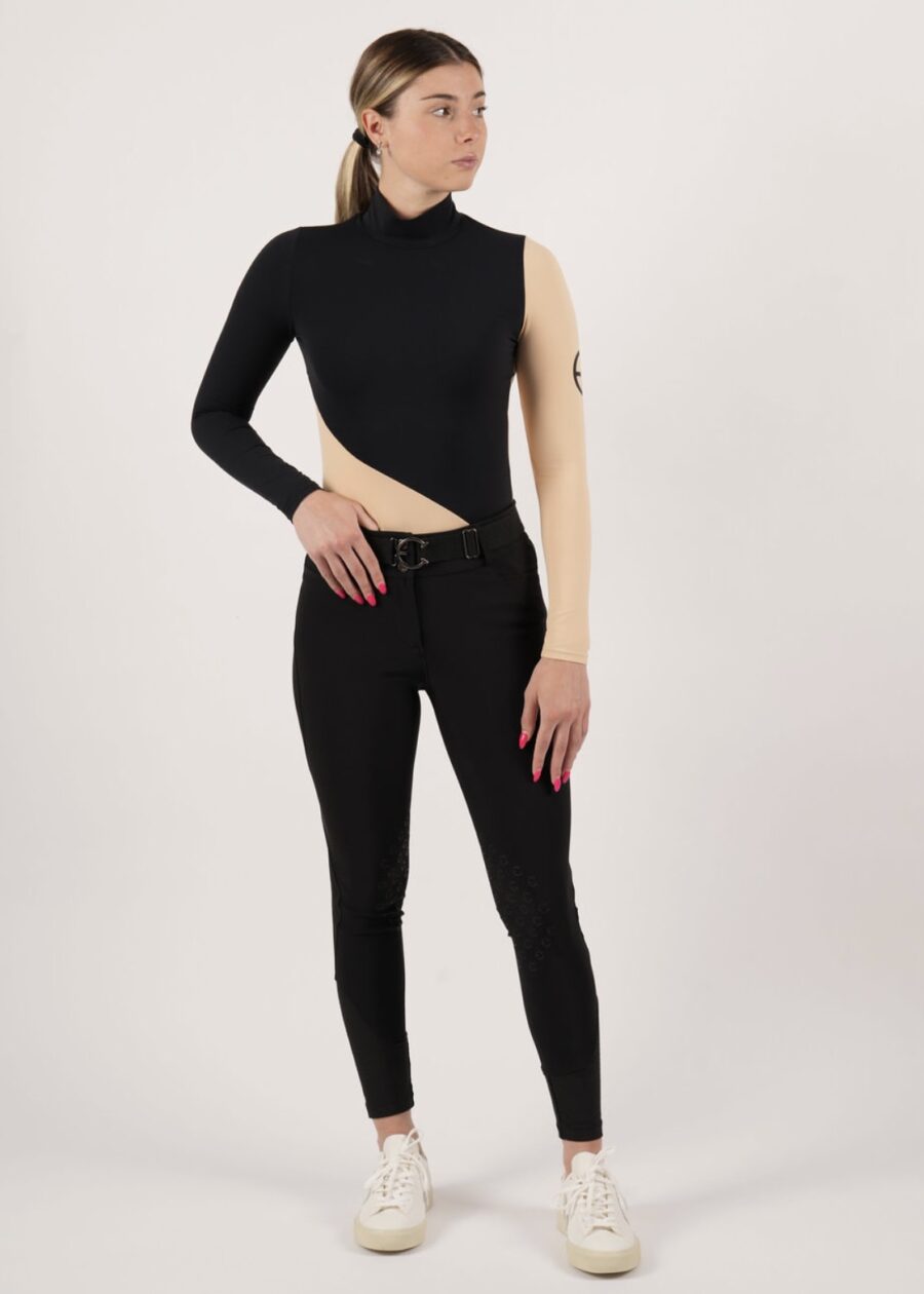 Woman wearing a unique black asymmetrical top and matching black pants.