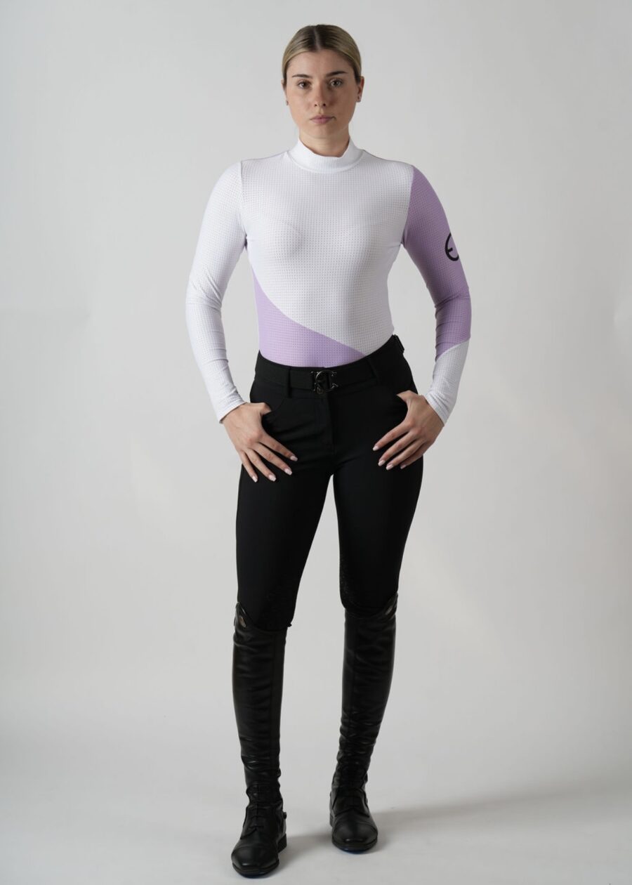 Woman wearing a white and purple long-sleeve top with black pants.