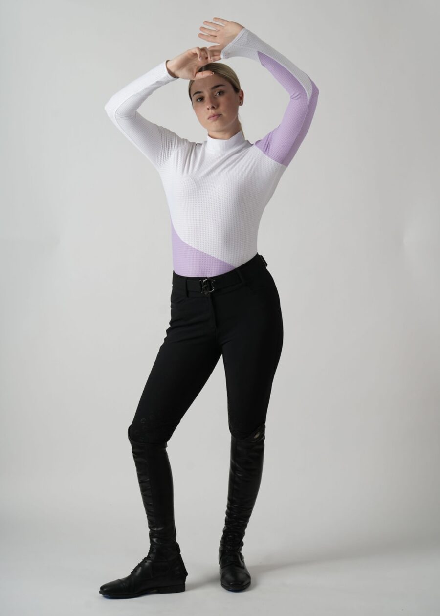 Woman in white long-sleeve top and black pants posing confidently.