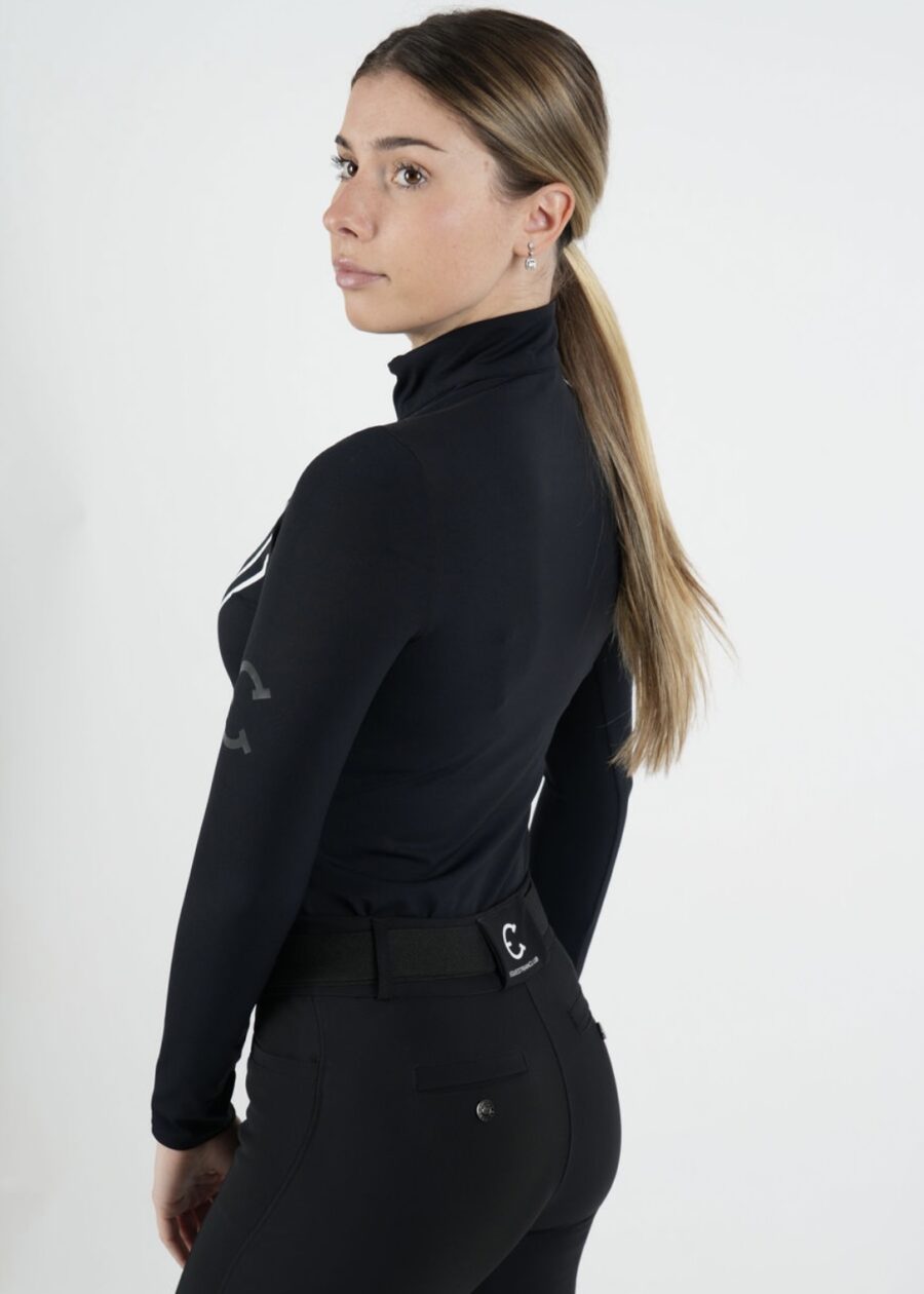 Woman in a black turtleneck and pants looking over her shoulder.
