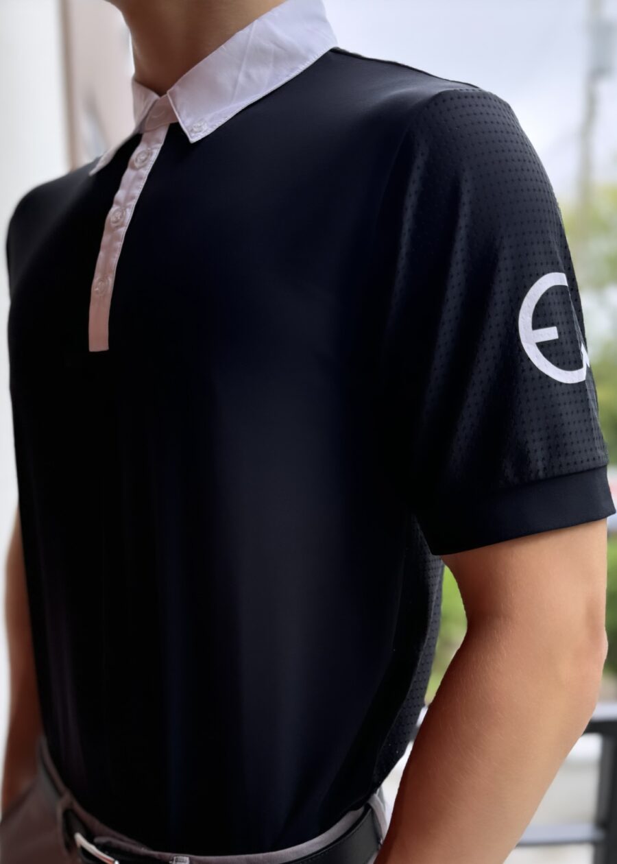 Person wearing a black polo shirt with a white logo on the sleeve.