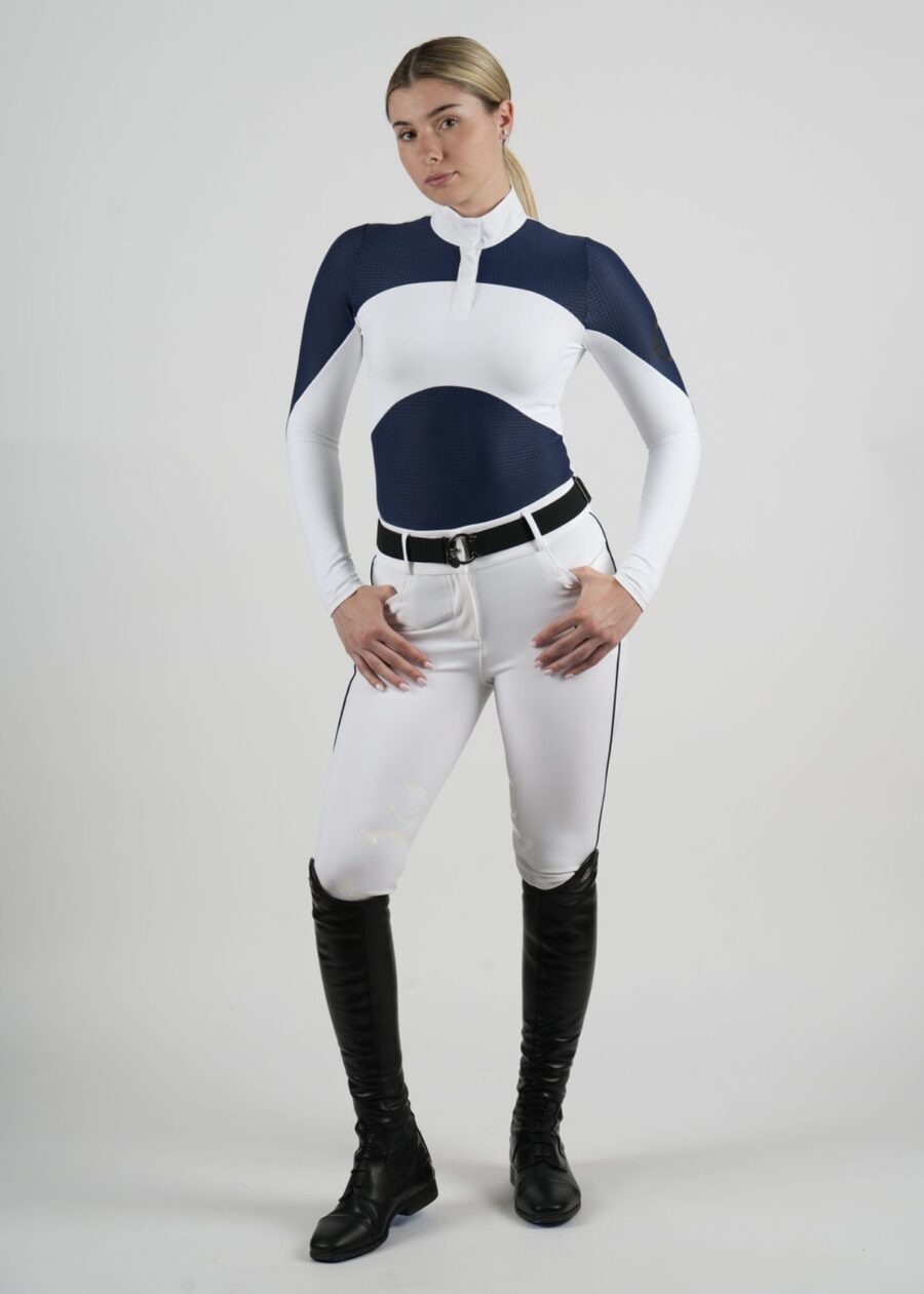 Person dressed in a stylish equestrian outfit with a cape and riding boots.