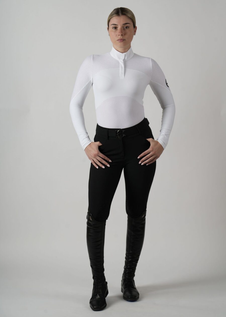 Person in white long-sleeve top and black pants posing against plain background.